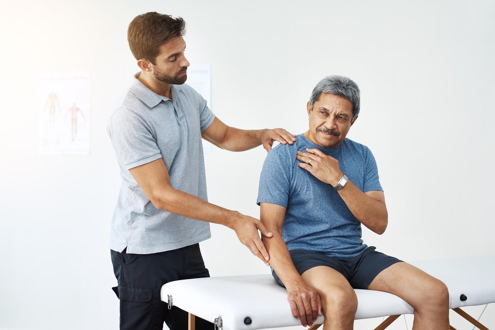 Physiotherapist gently assessing a senior man’s shoulder